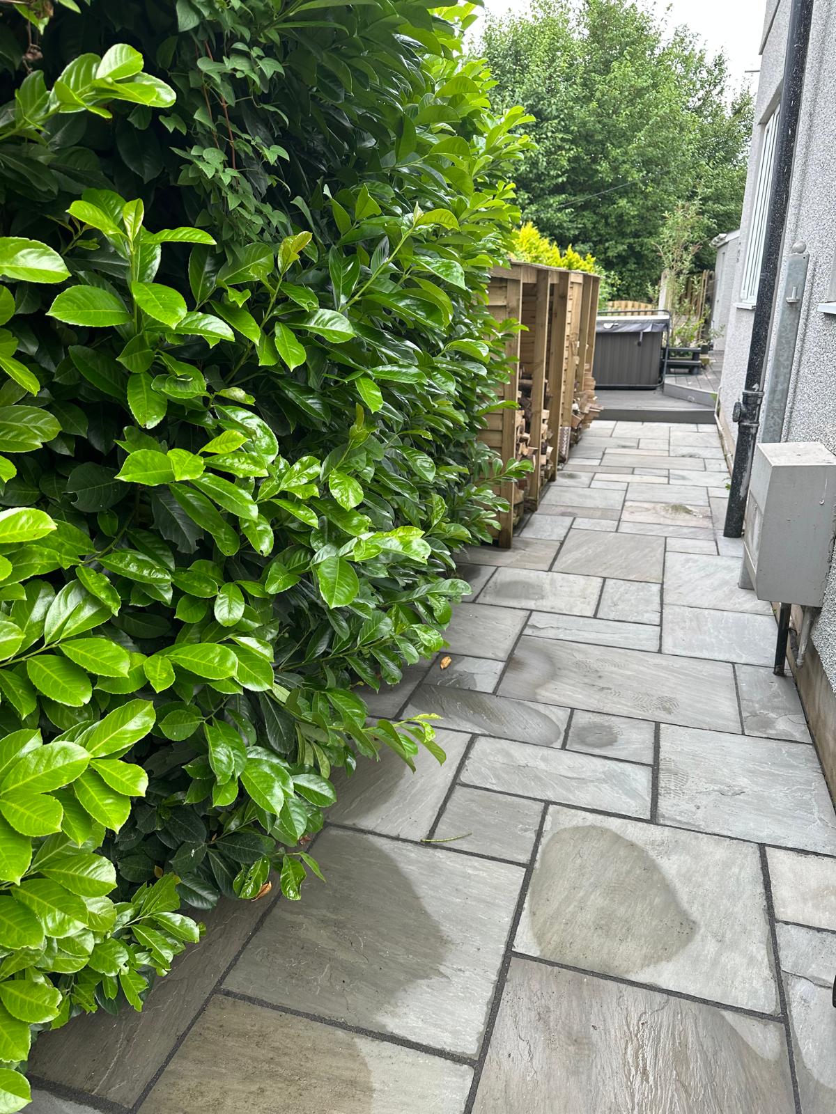 Completed stone patio path beside established hedging — South Wales garden works