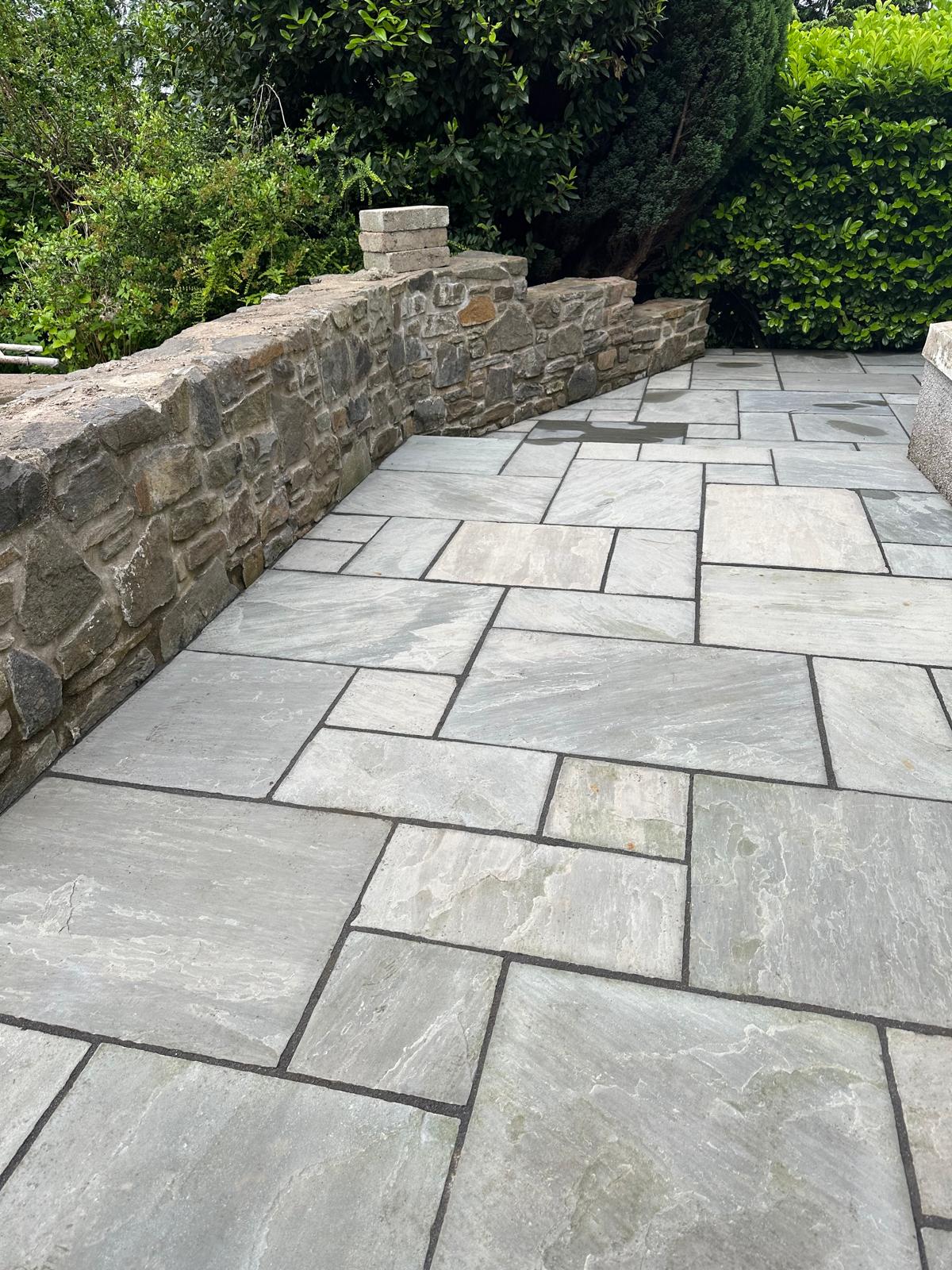 Finished patio with low stone wall and landscaping — South Wales garden project